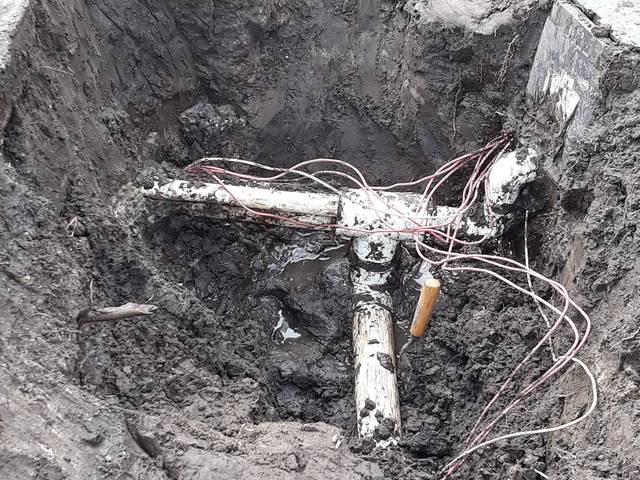 An excavated irrigation valve box showing pipe and wiring